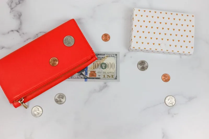 A red wallet with coins and a gift box