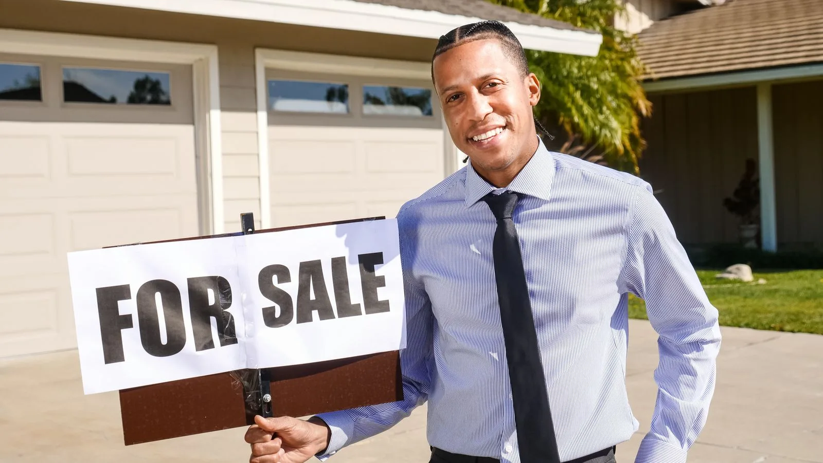 A real estate agent holding a For Sale sign